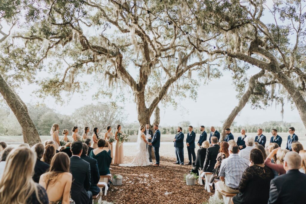 wedding ceremony outdoors under large oak tree at legacy at oak meadows